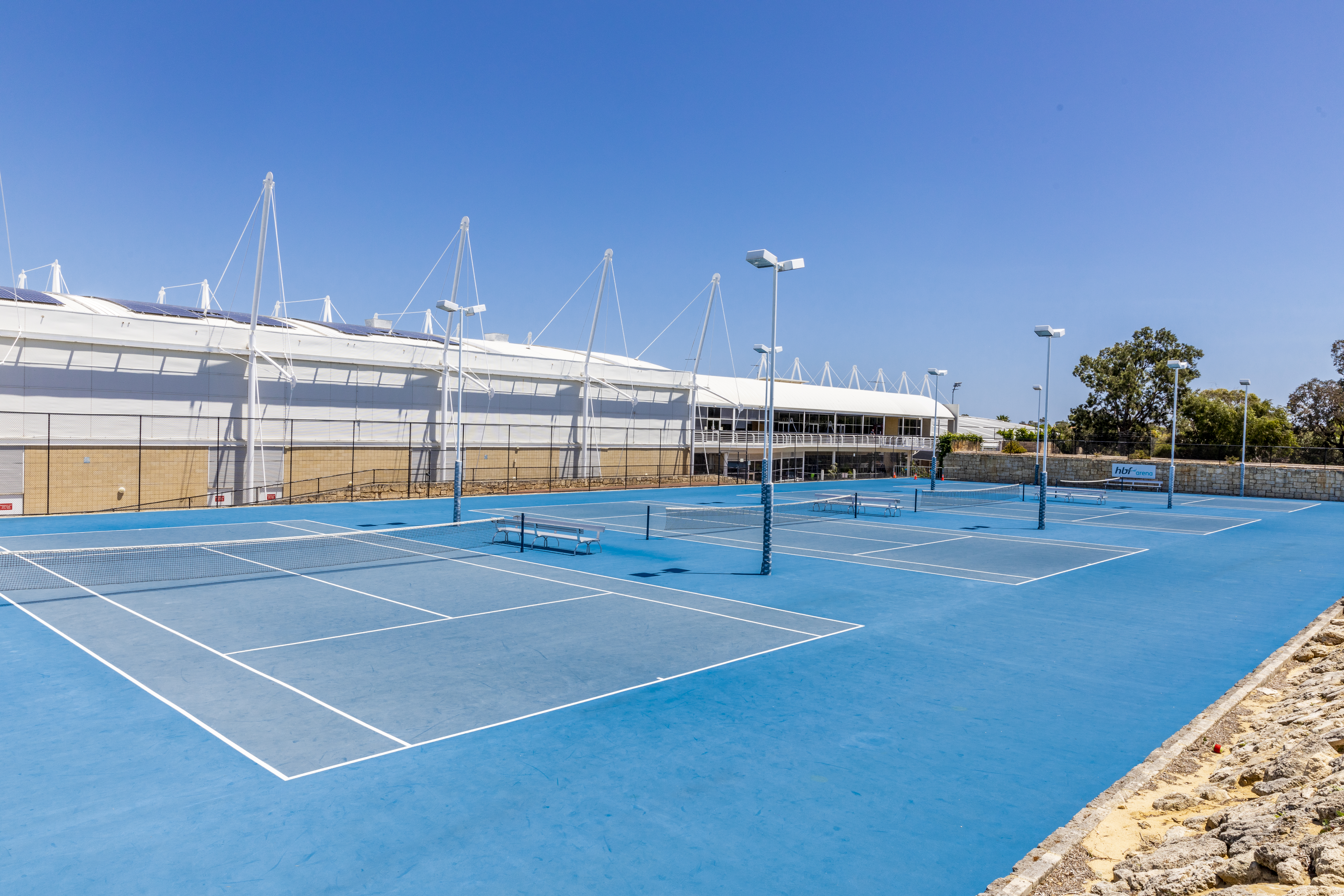 A photo of multiple outdoor tennis courts side by side at Arena Joondalup