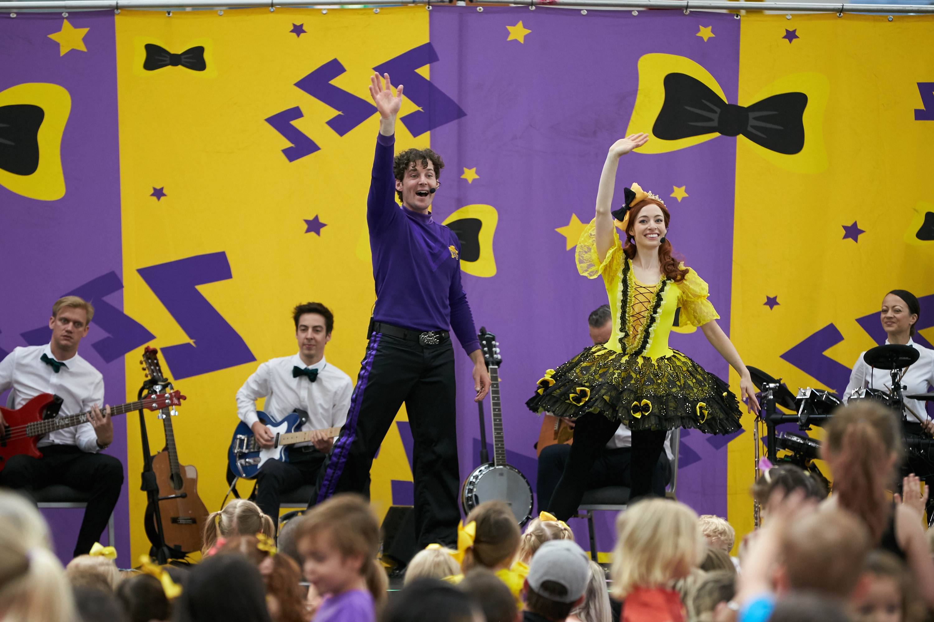 A photo of two members of The Wiggles waving to a crowd of spectators