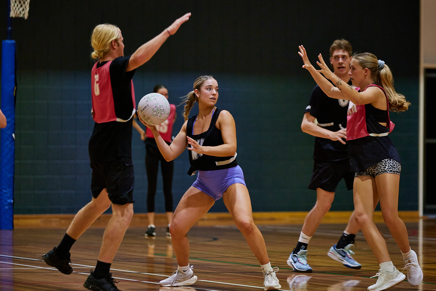 A photo of a woman attempting to throw a netball whilst being defended