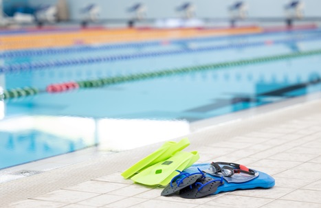 Kickboard, flippers, hand paddles, cap and goggles by the side of a 50m pool