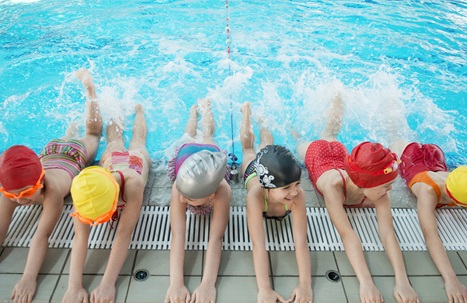Children in swimming lesson kicking on the side of the pool