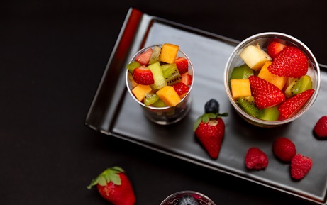 A top down photo of fruit in and around cups and bowls